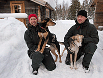 Madeleine och Per-Johan Göransson tillsammans med två av draghundarna framför huskucabin. Husku är jämtska och betyder duktig. Stugan är duktig på att göra vildmarken tillgänglig för rullstolsbundna.